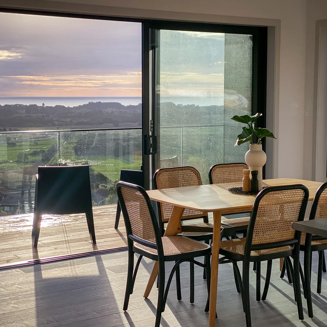 A dining table staged by HomeStaged, looking out over the sea at sunset