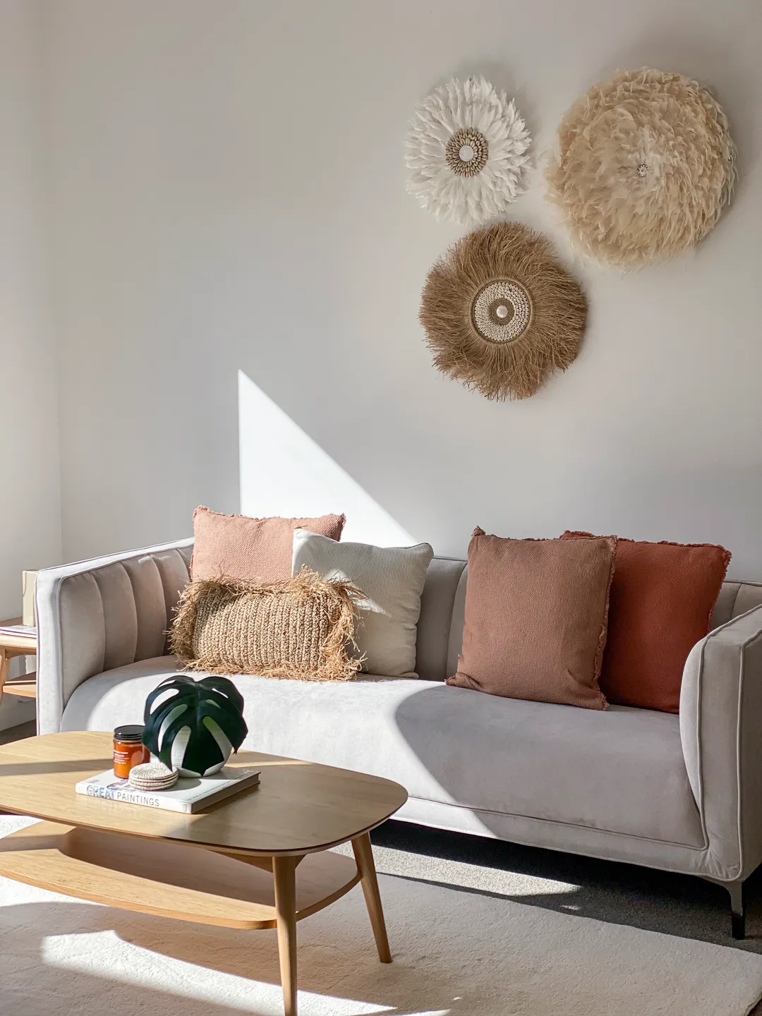 A sunlit lounge staged by HomeStaged, with a pale sofa, terracotta cushions and woven wall hangings